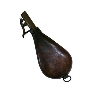 Peut inclure: Une poire à poudre en forme de poire, de couleur brun foncé, dotée d'un bec métallique avec un mécanisme à levier à ressort intégré pour la distribution. Le corps présente une texture lisse et usée, avec un petit anneau métallique à la base.