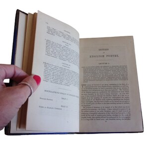 Puede incluir: Un libro abierto con una cubierta azul. El libro se titula "Lectures on English Poetry" y la p&aacute;gina est&aacute; abierta en la primera lecci&oacute;n. El texto de la p&aacute;gina trata sobre la importancia de estudiar la poes&iacute;a inglesa.