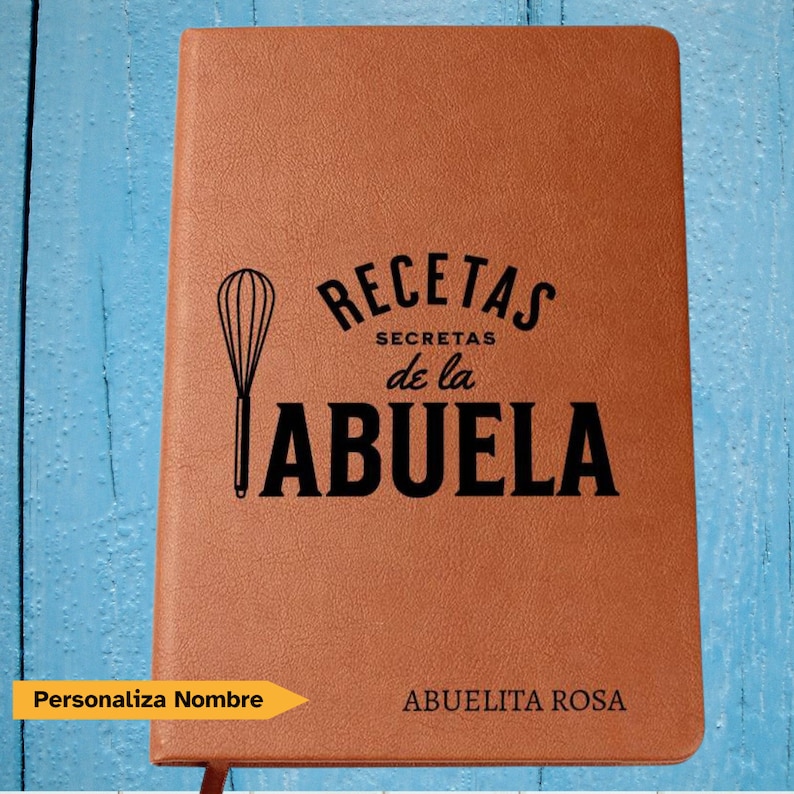 May include: A tan leather-like notebook featuring a black whisk icon and the text RECETAS SECRETAS de la ABUELA printed on the front cover. The bottom right corner displays the personalized text ABUELITA ROSA in a clean black font.