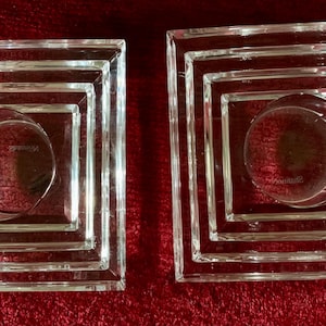 May include: Two clear glass square candle holders with a layered design. Each holder has four layers of square frames.