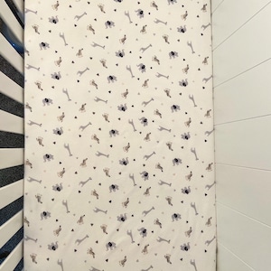 May include: White crib sheet with a repeating pattern of gray elephants, giraffes, and zebras. The pattern also includes small gray triangles.