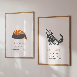 May include: Two framed art prints with a Halloween theme. One features a bowl of orange food with the text "BEWARE! MONSTER FEEDING." The other shows a dog skeleton with the text "MR MILO'S HAUNTED HEADQUARTERS."