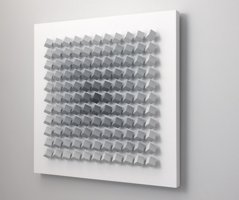 May include: A white wall with a gray and white geometric pattern made of squares. The squares are arranged in a grid pattern and are of varying sizes. The pattern is three-dimensional and creates a sense of depth.