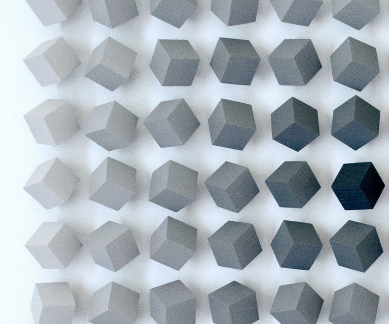 May include: A wall display of 36 small, gray, cube-shaped objects arranged in a grid pattern. The cubes are made of a smooth, matte material and are evenly spaced apart.