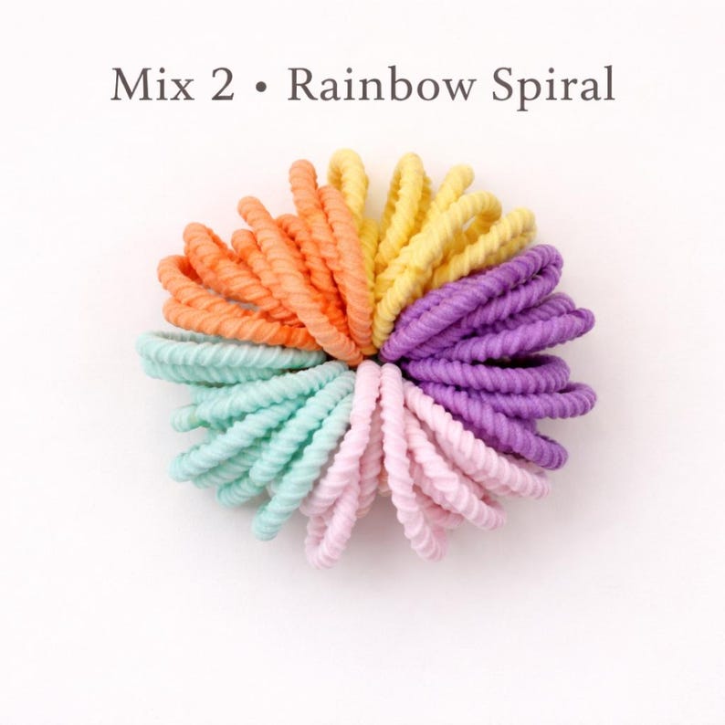K&ouml;nnte beinhalten: Eine Sammlung von spiralf&ouml;rmigen Haargummis, die kreisf&ouml;rmig angeordnet sind und mit Mix 2 &bull; Rainbow Spiral beschriftet sind. Die Haargummis haben eine gerippte Textur und sind in den Farben Orange, Gelb, Lila, Hellrosa und Hellminzgr&uuml;n.