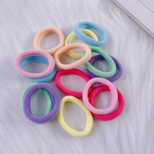 May include: A collection of colorful hair ties in pastel shades of pink, blue, yellow, and green. The hair ties are made of soft, stretchy fabric and are perfect for holding back hair.
