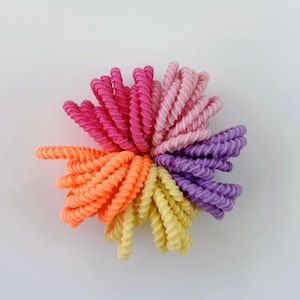 May include: A set of colorful hair ties in pink, orange, yellow, and purple. The ties are made of a soft, stretchy material and are perfect for holding hair in place.