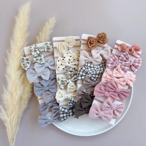 May include: A set of 20 hair bows in various colors and patterns, including floral, polka dot, plaid, and solid colors. The bows are arranged on cards with a white background.