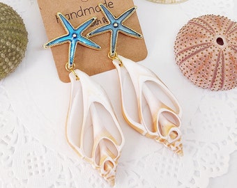 Könnte beinhalten: Handgefertigte Ohrringe mit einem blauen Seestern-Anhänger und einem weißen Muschel-Anhänger. Die Ohrringe werden auf einer braunen Karte mit dem Text "Handmade with Love" präsentiert.