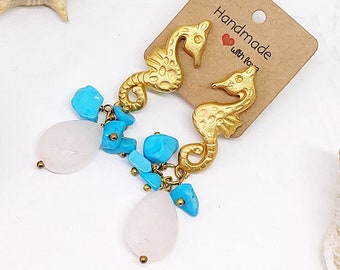 May include: Gold seahorse earrings with turquoise and white stone accents. The earrings are handmade and come with a brown card that says "Handmade with love".