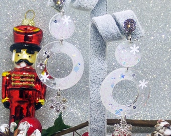 Boucles d'oreilles de Noël en résine cristal effet glace, ornées de cristaux de neige et de paillettes.