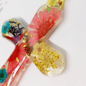 Dia de los Muertos inspired cross-shaped resin pendant with inclusions of real dried flowers
