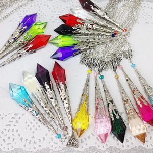 May include: A set of 12 crystal point pendants with silver chains. The crystals are in various colors, including blue, green, red, purple, and yellow.