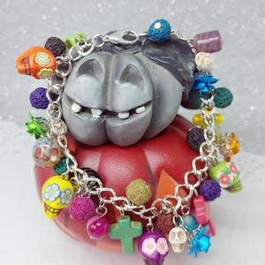 Pulsera del Día de los Muertos con calaveras y cruces de howlita, cuentas de cristal checo de colores y piedra de lava, rosas de resina y metal.