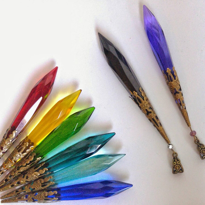 May include: A set of colorful crystal pendants with ornate metal accents. The pendants are shaped like teardrops and come in a variety of colors, including red, yellow, green, blue, and purple.