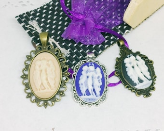 May include: Three cameo pendants with ornate frames. The cameos feature white figures on a background of ivory, blue, and black.