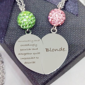 May include: Two silver necklaces with heart-shaped pendants. One pendant says "unusually and exceedingly peculiar and altogether quite impossible to describe" and the other says "Blonde."