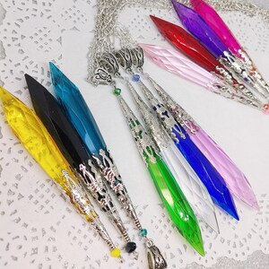 May include: A set of nine crystal point pendants with silver chain and ornate silver accents. The crystals are in various colors, including yellow, black, teal, green, clear, blue, pink, red, and purple.