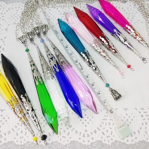 May include: A set of 10 crystal point pendants with silver-tone chain and ornate metal accents. The pendants are in various colors, including yellow, black, green, white, blue, pink, and purple.