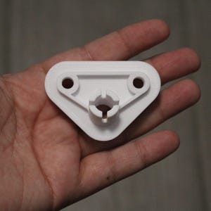 May include: White plastic triangular bracket with two holes and a central opening.