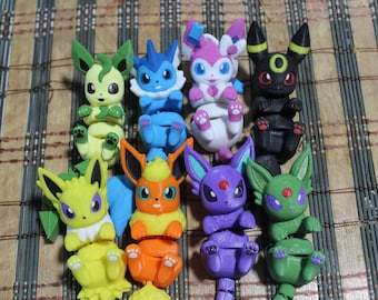 May include: A collection of nine colorful, articulated figurines of various Pokémon characters. The figures are in various colors, including green, blue, pink, black, yellow, orange, purple, and green. Each figure has a unique design and pose.