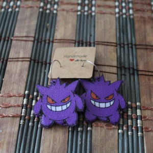Puede incluir: Pendientes Gengar Pokemon de color morado y blanco con aros plateados. Los pendientes están hechos a mano con amor.