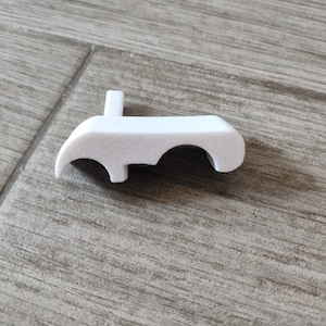 Puede incluir: Pomo de plástico blanco con tres agujeros, diseñado para una puerta o ventana.