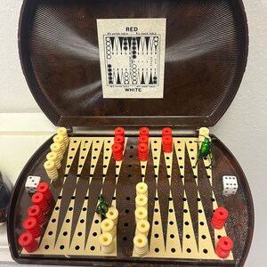 May include: A brown wooden game board with a checkerboard pattern. There are red and white checkers on the board, as well as two green beetles. The board is in a brown wooden case with the words "RED" and "WHITE" printed on the inside of the lid.