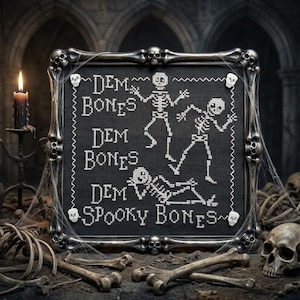 May include: A square cross-stitch embroidery on black fabric featuring white skeletons and the text "DEM BONES DEM BONES DEM BONES SPOOKY BONES". The piece is encased in a dark, metallic frame molded to resemble interconnected human bones.