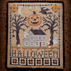 May include: Cross-stitch Halloween design featuring a house, jack-o'-lantern, trees, and ghosts. The word "HALLOWEEN" is stitched across the bottom. The design is framed with a black border and set against a brown background.