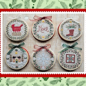 May include: Six embroidered Christmas ornaments in wooden hoops, each with a unique design. The ornaments feature a red cardinal, the word "Noel", a boot, a house, a snowflake, and a geometric pattern. Each ornament is adorned with a ribbon.