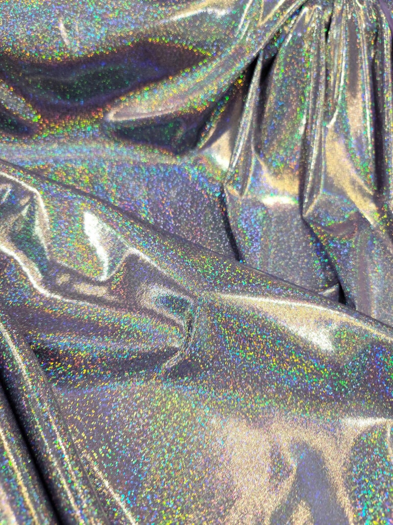 May include: Close-up of iridescent silver fabric with a subtle sparkle. The fabric has a smooth, shiny texture and is perfect for crafting or sewing projects.