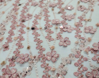May include: Pink floral embroidered lace fabric with sequins and beads. The fabric has a delicate, feminine look and would be perfect for a variety of projects, such as dresses, skirts, and tops.