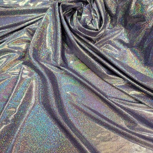 May include: A close-up of iridescent silver fabric with a subtle sparkle. The fabric is wrinkled and folded, showing its texture.