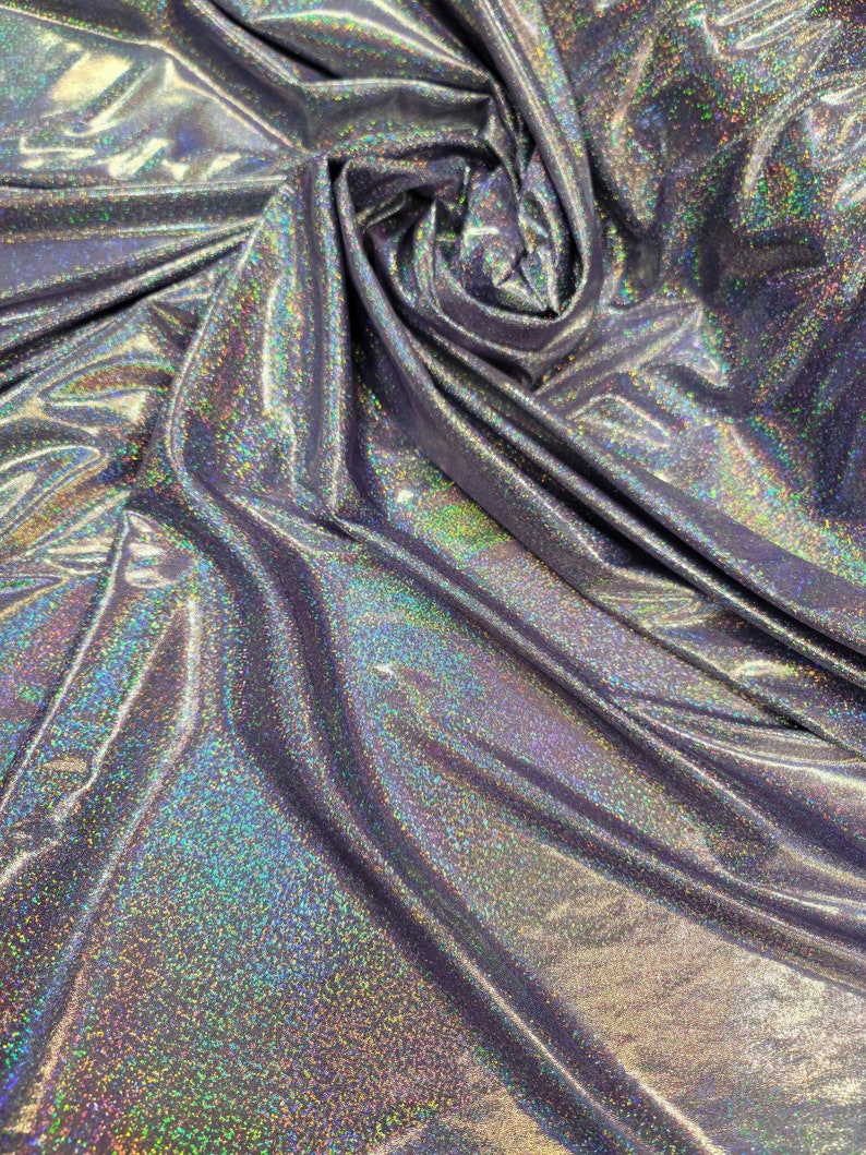 May include: A close-up of iridescent silver fabric with a subtle sparkle. The fabric is wrinkled and folded, showing its texture.