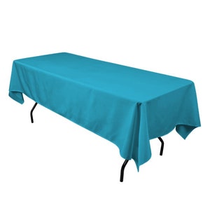 Puede incluir: Un mantel rectangular turquesa drapeado sobre una mesa con patas de metal negro.