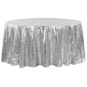 Könnte beinhalten: Eine runde Tischdecke aus silbernen Pailletten. Die Tischdecke ist aus einem schimmernden Stoff mit einem dezenten Glanz.