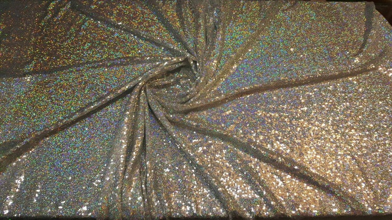 Op de afbeelding: Een close-up van iriserende zilveren en gouden paillettenstof. De stof is een glinsterende, glimmende stof met een subtiele glans.