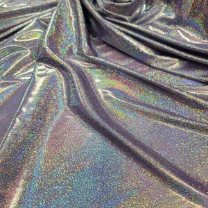 May include: Close-up of iridescent silver fabric with a subtle sparkle. The fabric is wrinkled and folded, showing its texture.