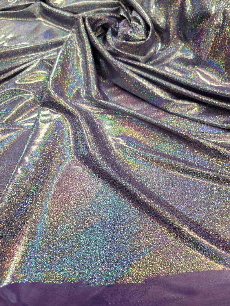 May include: Close-up of iridescent silver fabric with a subtle sparkle. The fabric is wrinkled and folded, showing its texture.