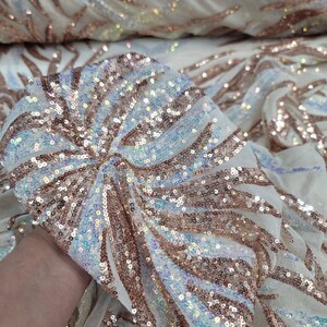 May include: White mesh fabric with iridescent sequins in a rose gold colour. The sequins are arranged in a swirling pattern.