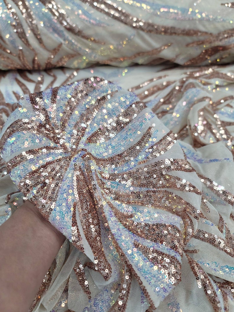 May include: White mesh fabric with iridescent sequins in a rose gold colour. The sequins are arranged in a swirling pattern.