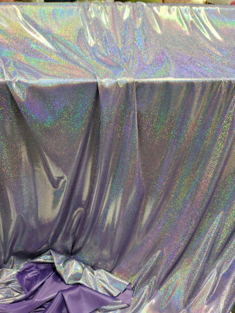 May include: A silver iridescent fabric with a subtle sparkle. The fabric is folded and draped over a purple surface.