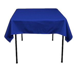 Puede incluir: Un mantel de mesa cuadrado de color azul real drapeado sobre una mesa de metal negro. El mantel es liso y plano.