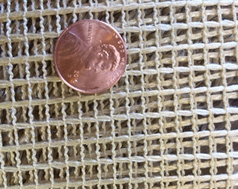 May include: Close-up of a beige mesh fabric with a US penny on top. The penny is used to show the scale of the mesh.