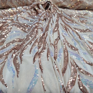 May include: White mesh fabric with iridescent sequins in a rose gold colour, arranged in a wavy pattern.