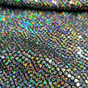 May include: Close-up of iridescent fabric with a pattern of small, round sequins. The sequins are arranged in a repeating pattern and create a shimmering effect.