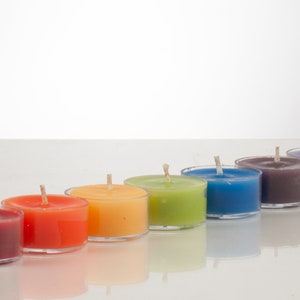 May include: A row of eight tealight candles in a rainbow of colors, from red to purple.