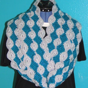 May include: A teal and silver crocheted infinity scarf with a textured, flower-like pattern.