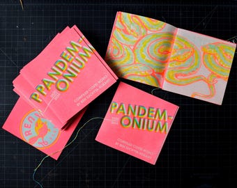以下が含まれることがあります： 「Pandemonium 2020-2024: Compiled Covid Works by Ren Suchyta-Kolany」というタイトルのピンクと緑の書籍の束。
